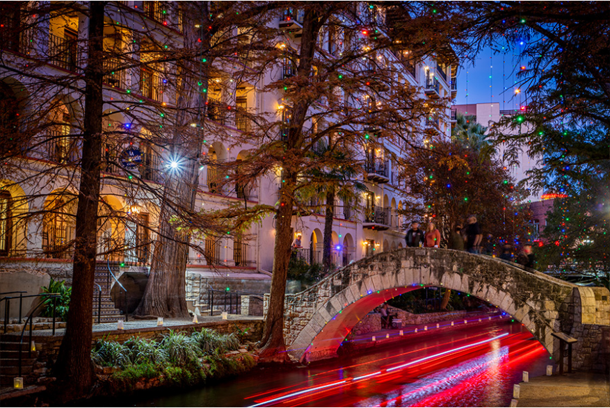 River Walk lit up with holiday lights and glow from river barge