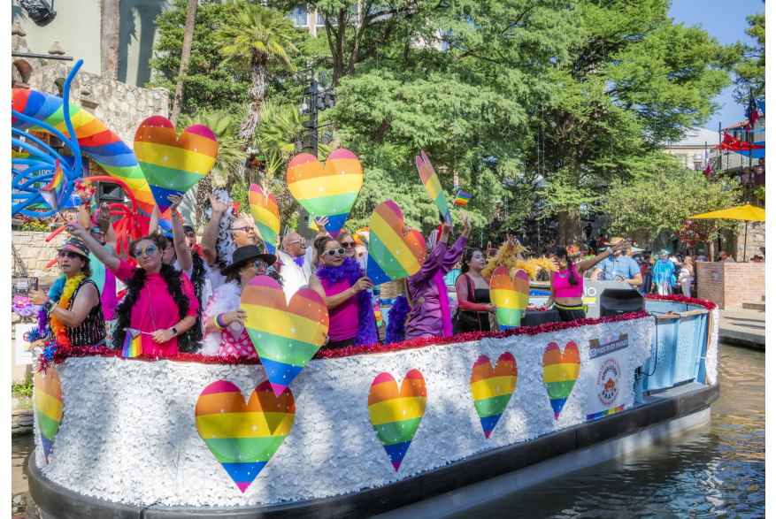 River barge with rainbow hearts and people floating on River Walk