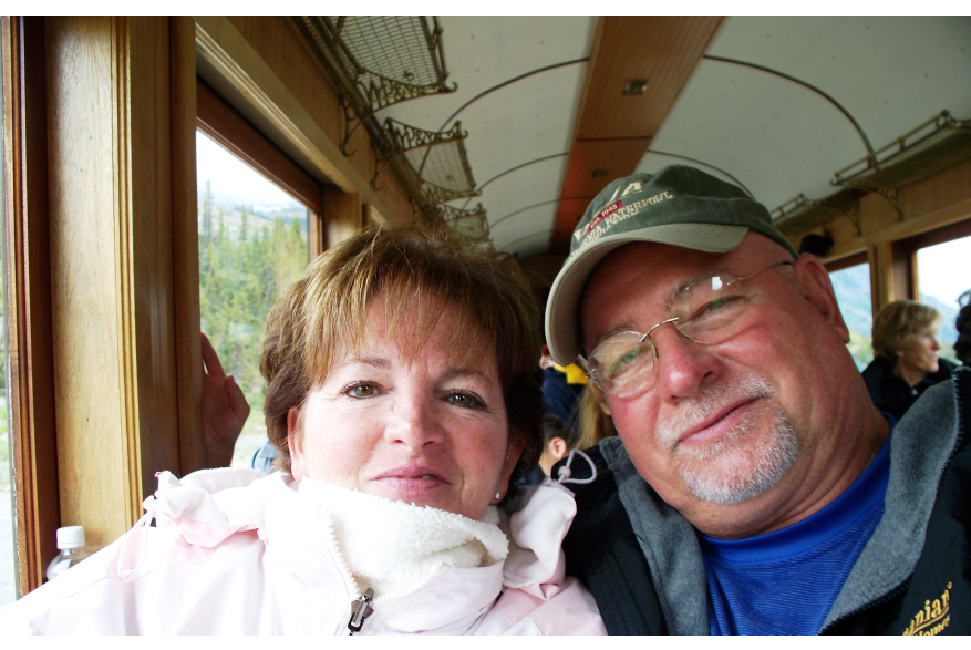 a woman with short hair and white jacket poses with man in ball cap and glasses on White Pass train car