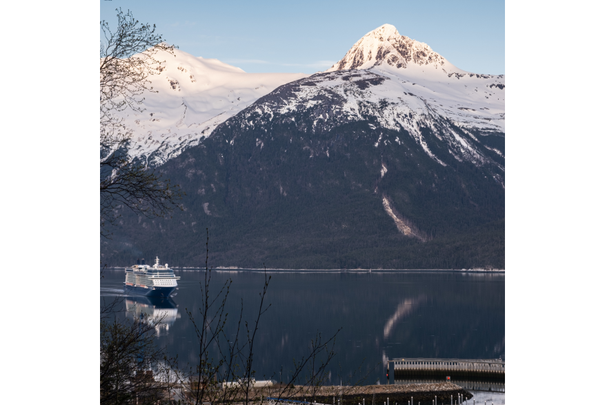Cruise ship arriving in Skagway on calm waters in early morning with snow capped mountains in the background