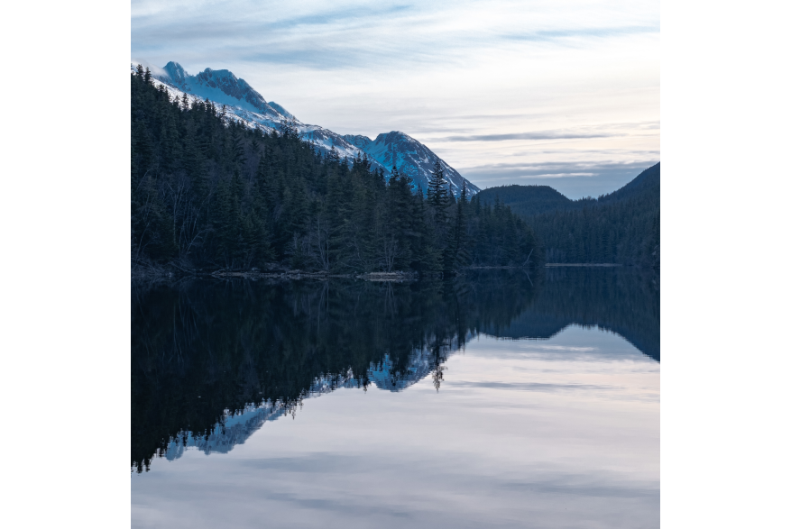 Early morning at Lower Dewey Lake on calm waters the mirror image of mountains, trees and cloudy skies are visible