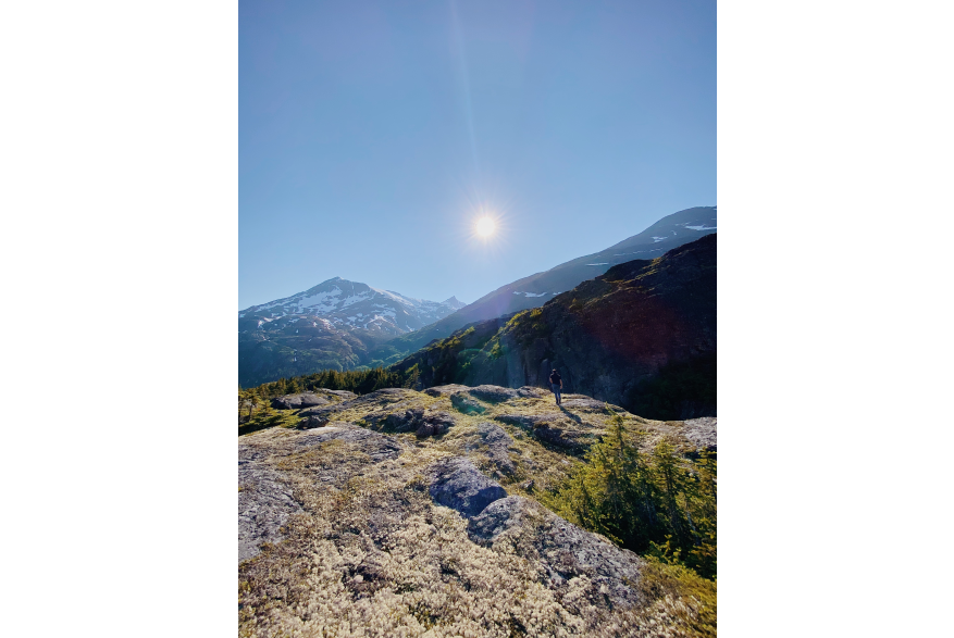 clear blue sky with sun shining on the rocky lichen covered rocks of White Pass Summit overlooking the valley of Skagway.