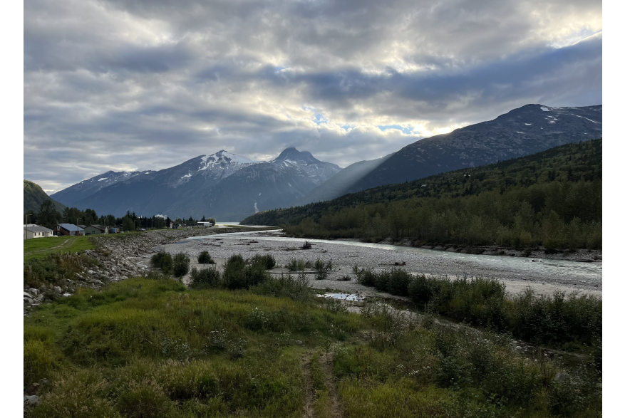 Sun shining through the mountains onto a much smaller Skagway River in early September