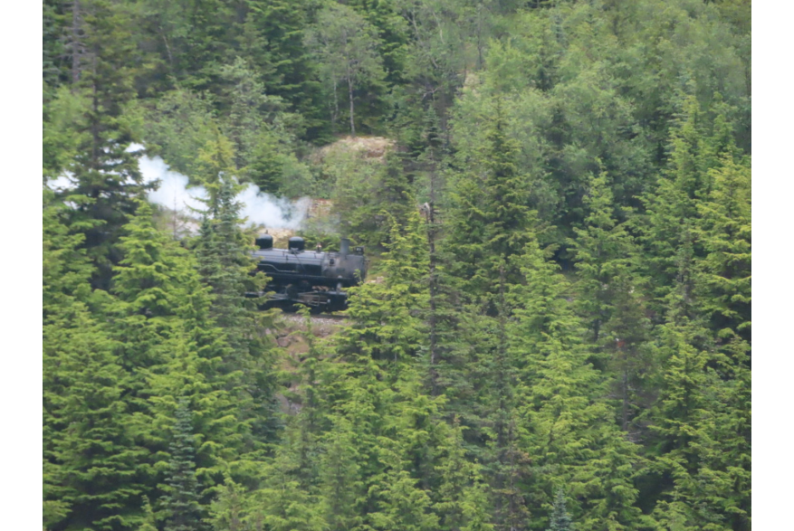 White Pass Train going through mountain with steam