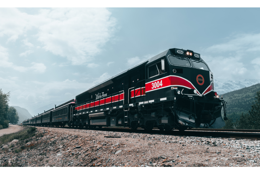 Trains! A white pass diesel locomotive loaded with excited passengers leaving Skagway on a beautiful summer morning.