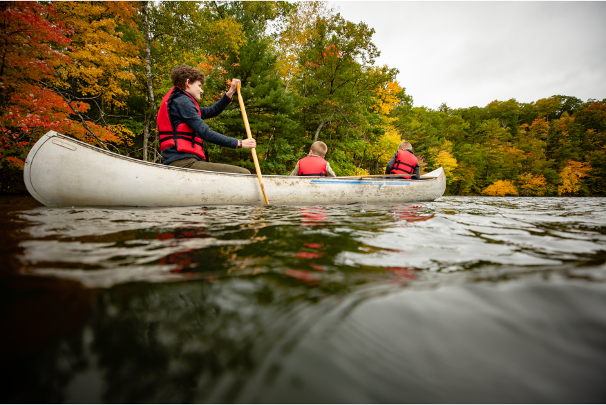 family canoeing with fall color leaves