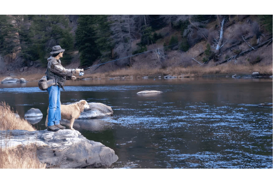 A person enjoying fly fishing in Saratoga, Wyoming with their loyal dog by their side, one of the many exciting things to do in the area.