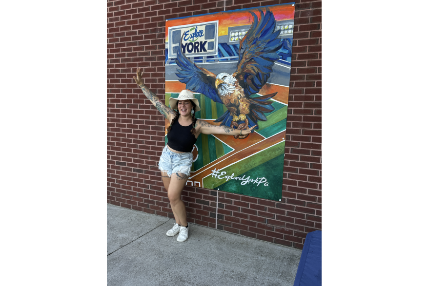Annelise Vuono posing with her handpainted mural inside WellSpan Park