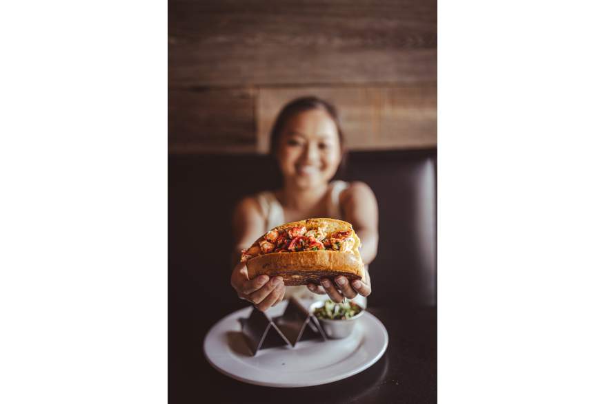 a very happy girl holding up a lobster roll at Rockfish Public House