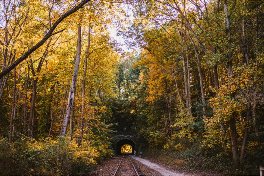 A couple bikes through the historic Howard Tunnel on the rail trail during autumn
