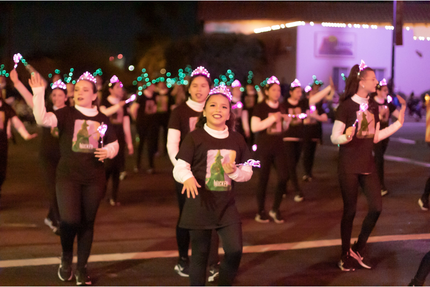 Young girls marching with lit up pink tiaras and green wands to represent the Broadway Musical "Wicked"