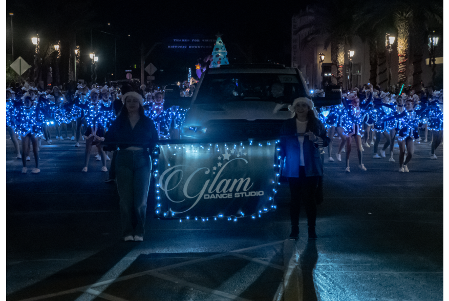 Winner of best performance Glam Dance Studio marching behind their banner down main street all in Blue Christmas Lights