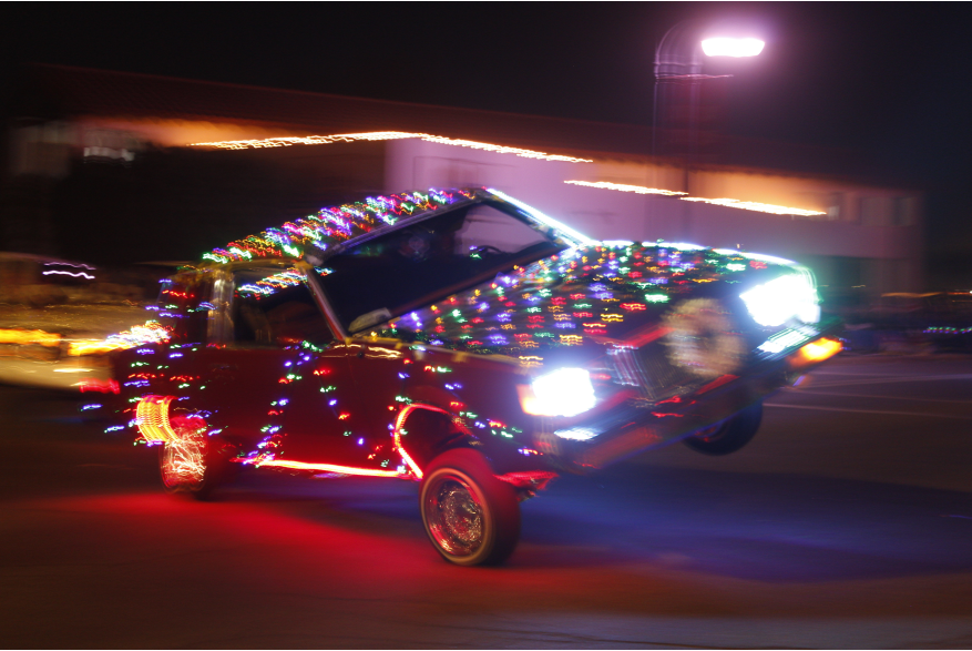 Lowrider Dress in Christmas lights driving with front Drivers Wheel in the air.