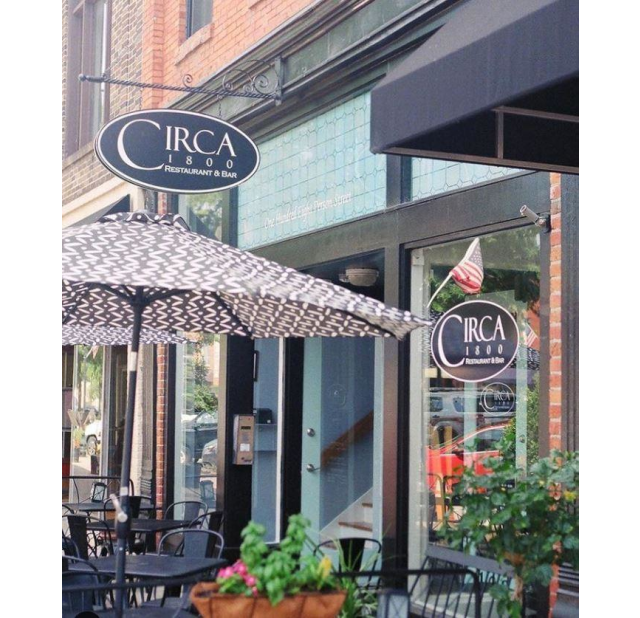 Outdoor dining area in front of Circa 1800, a popular downtown Fayetteville, NC restaurant, with patio umbrellas and street views.