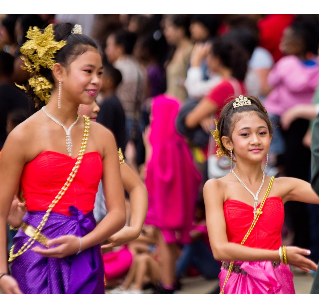 Two young girls in traditional Southeast Asian costumes performing a cultural dance at the International Folk Festival in Fayetteville, NC.