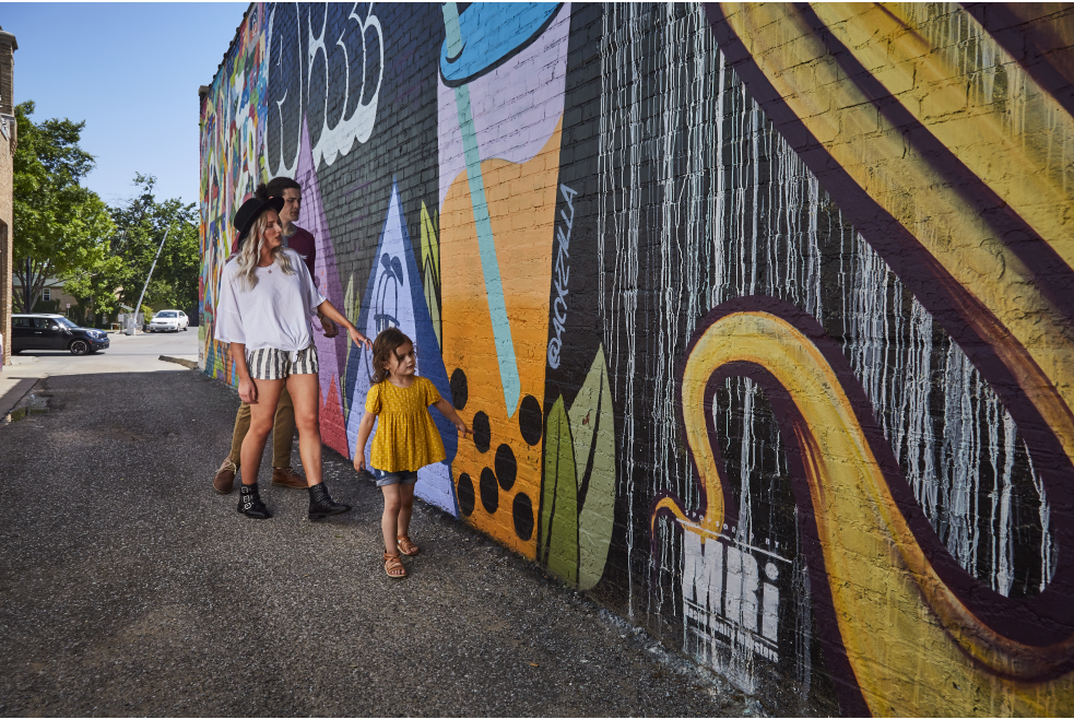 Mother, father and child viewing abstract Plaza Walls wall mural