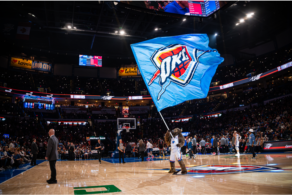 Rumble waving OKC Thunder flag at a basketball game