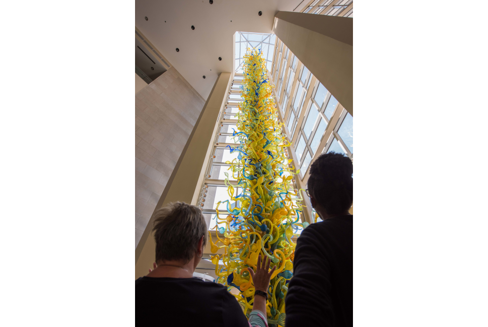 Two women admiring the Dale Chihuly glass art tower at the entrance of OKC's Museum of Art