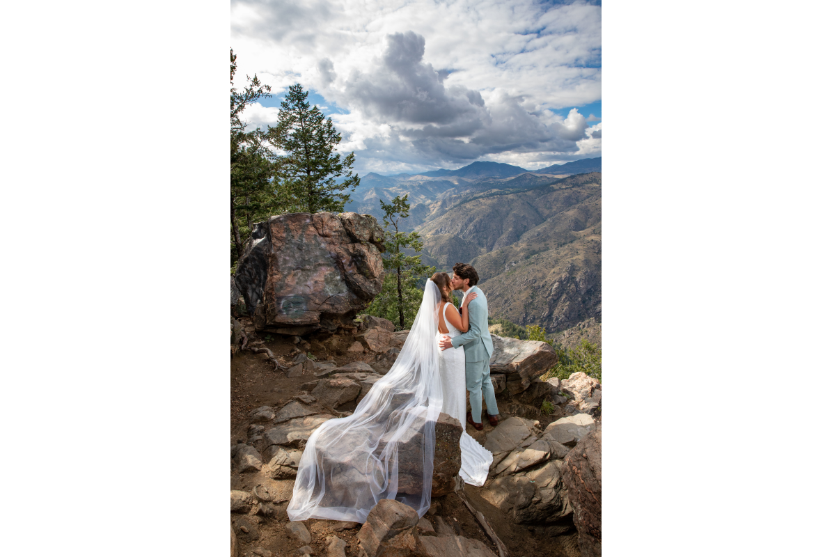 Bride and Groom embracing on a boulder lookout with majestic Clear Creek Canyon and Rocky Mountains in background