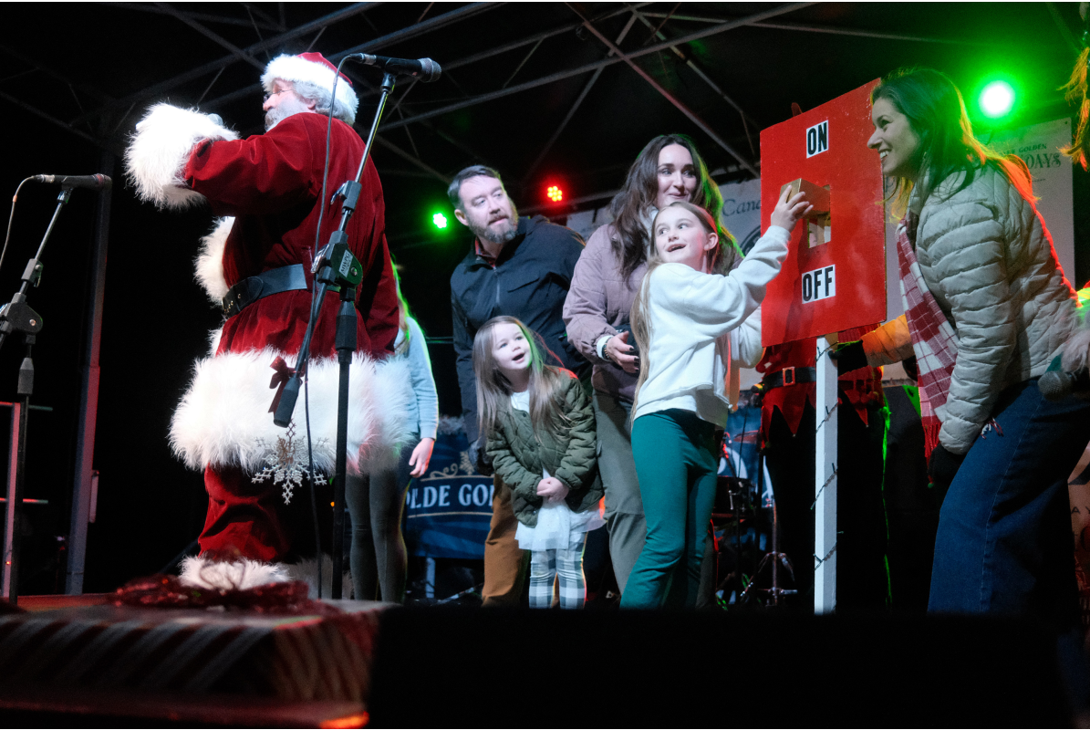 Santa and a local family stand on stage the child winner of the contest flips the switch to illuminate holiday lights in downtown Golden, CO.