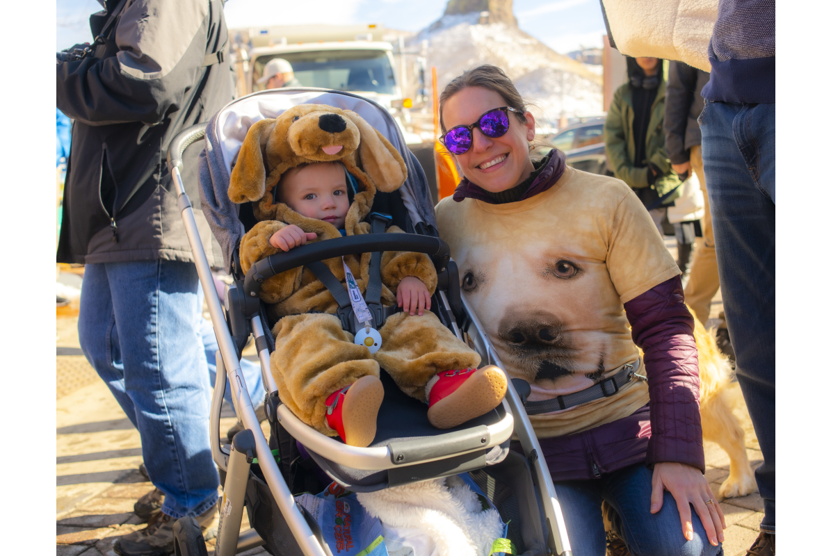 A baby dressed in a Golden retriever costume and parent with a golden retriever shirt at the 2022 Goldens in Golden event