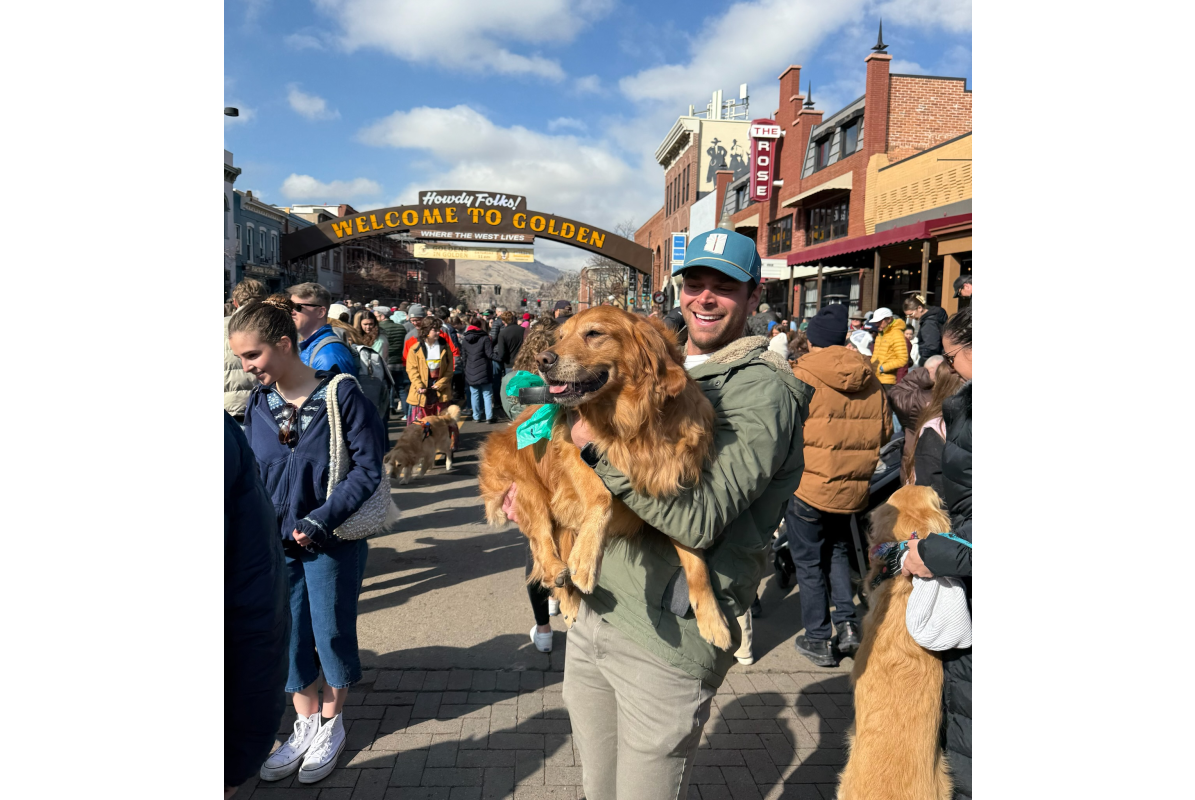 Goldens in Golden photos under the Golden Welcome Arch. a man holding a golden retriever