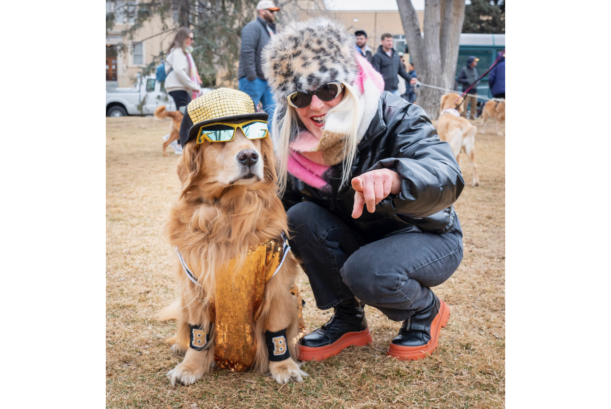 A golden retriever dressed up like a rock star with a costumed owner