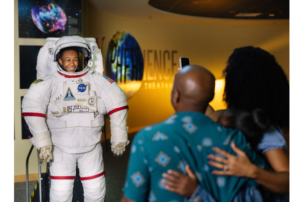 Family fun at INFINITY Science Center with child in astronaut suit with parents looking on