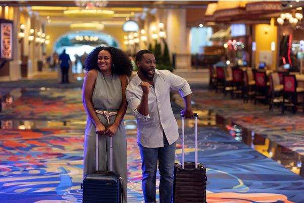 African American couple with suitcases excitedly walking the casino floor