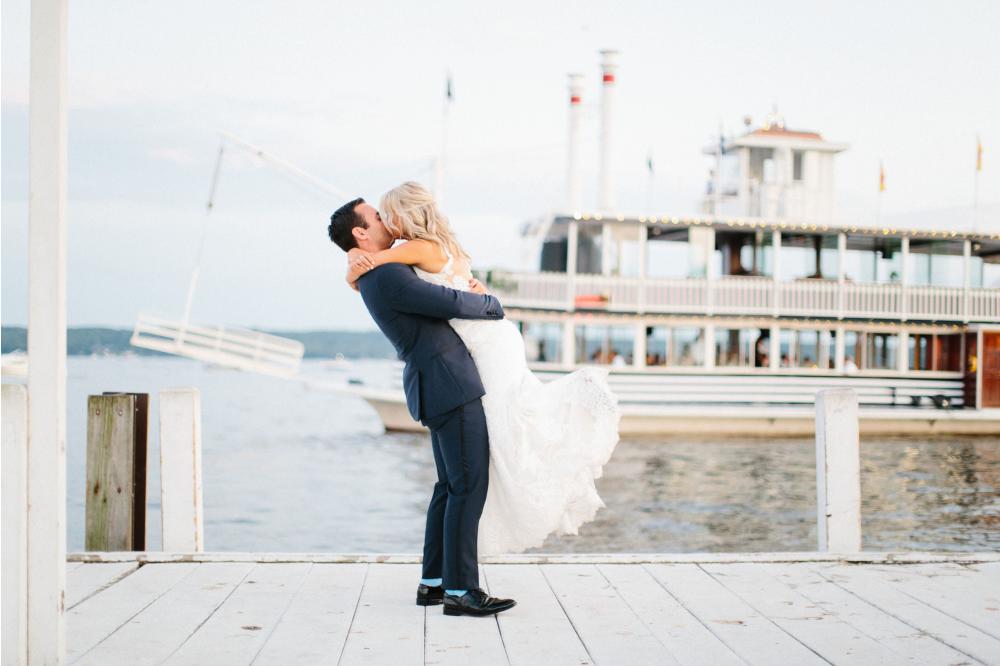 Newlyweds embrace as the Lady of the Lake Cruises Behind Them for Their Reception!