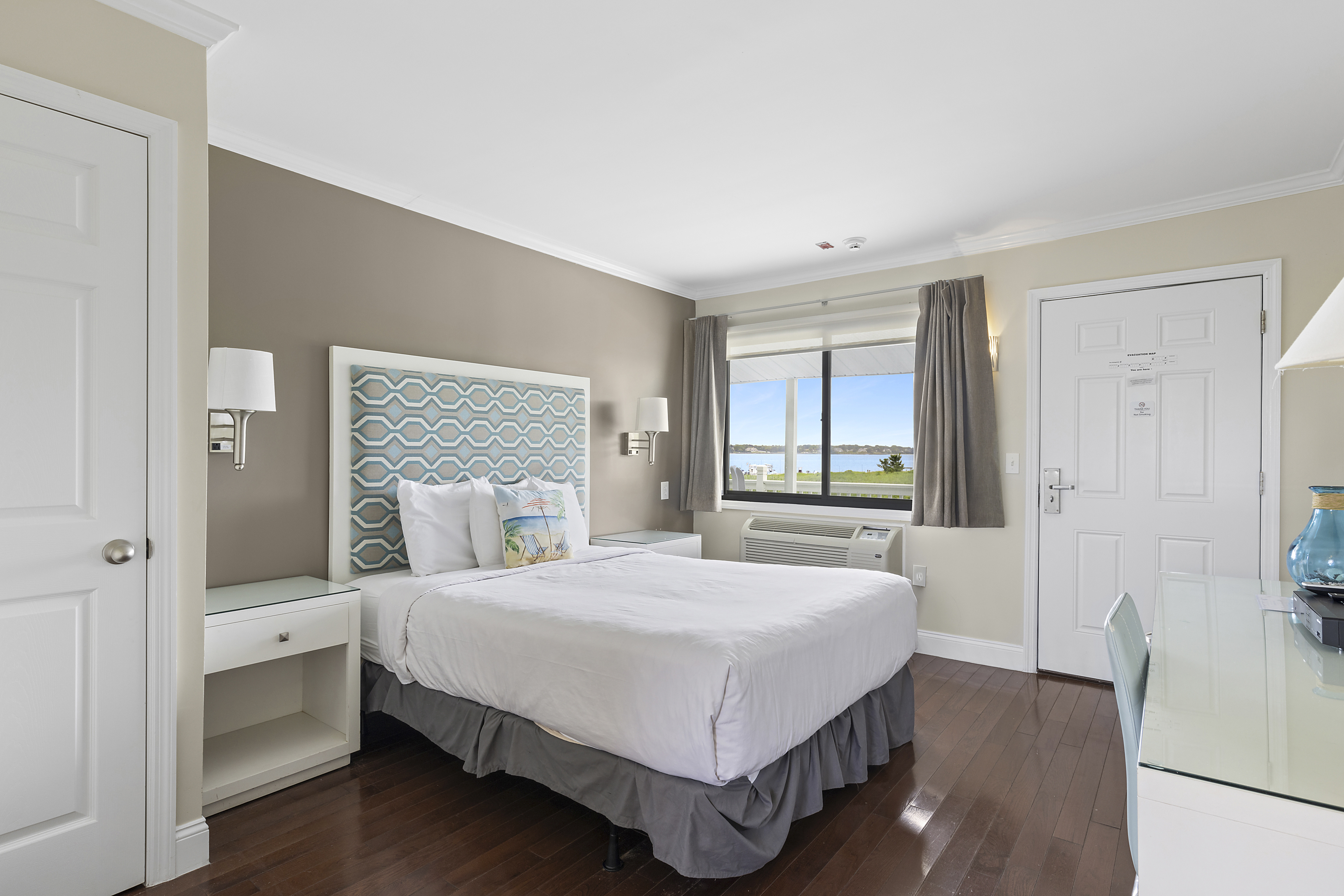Room Class - Balcony Queen - The Balcony Queen rooms are located on the second-floor of our two-story building, situated closer to Tiana Bay providing more immediate access to our various waterside amenities. The Balcony Twin rooms feature a shared balcony that boasts stunning views of Tiana Bay, which comes fitted with sitting chairs and a small side table. The Balcony Queen rooms feature one (1) queen-sized bed, a kitchenette, and a flat-screen TV. There are three (3) Balcony Queen rooms on our premises.