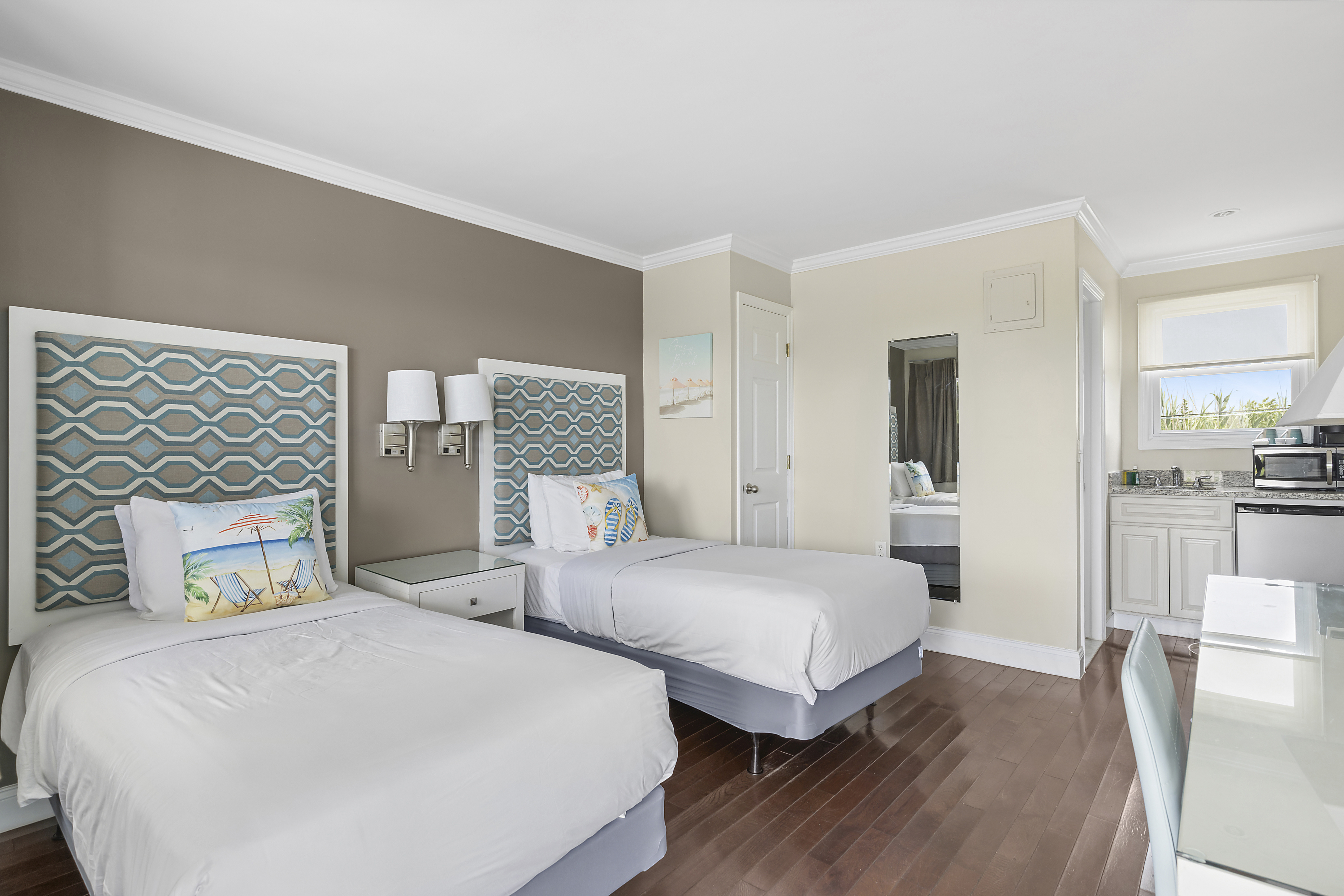 Room Class - Balcony Twin - he Balcony Twin rooms are located on the second-floor of our two-story building, situated closer to Tiana Bay providing more immediate access to our various waterside amenities. The Balcony Twin rooms feature a shared balcony that boasts stunning views of Tiana Bay, which comes fitted with sitting chairs and a small side table. The Balcony Twin rooms feature two (2) twin-sized beds, a kitchenette, and a flat-screen TV. There are two (2) Balcony Twin rooms on our premises.