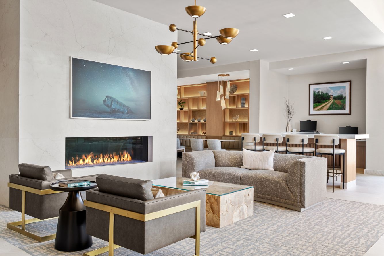 Lobby/Fireplace - Our inviting lobby featuring a fireplace, contemporary seating, and elegance gold accents that create a warm yet sophisticated atmosphere. With soft lighting and an open layout leading into the bar area, it's the perfect sport for guests to relax, socialize, or unwind by the fire in style.
