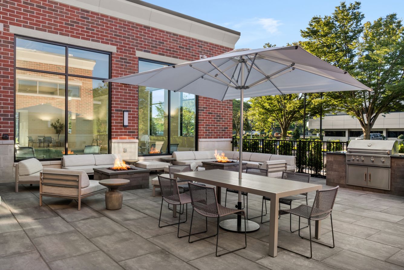 Outdoor Patio - Our outdoor patio offers a relaxed yet refined setting with plenty of seating, 2 fire pits, and spacious tables, shaded by umbrellas. Surrounded by greenery and natural light, it's the perfect spot for guests to gather, unwind, or enjoy a casual meal in a comfortable open-air environment.