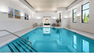 Indoor Pool - This serene indoor pool area offers a relaxing escape year-round, featuring a heated saltwater pool surrounded by natural light and comfortable lounge seating. The bright inviting space is perfect for a refreshing swim, a peaceful unwind, or leisurely start to the day in a calm, climate-controlled setting.