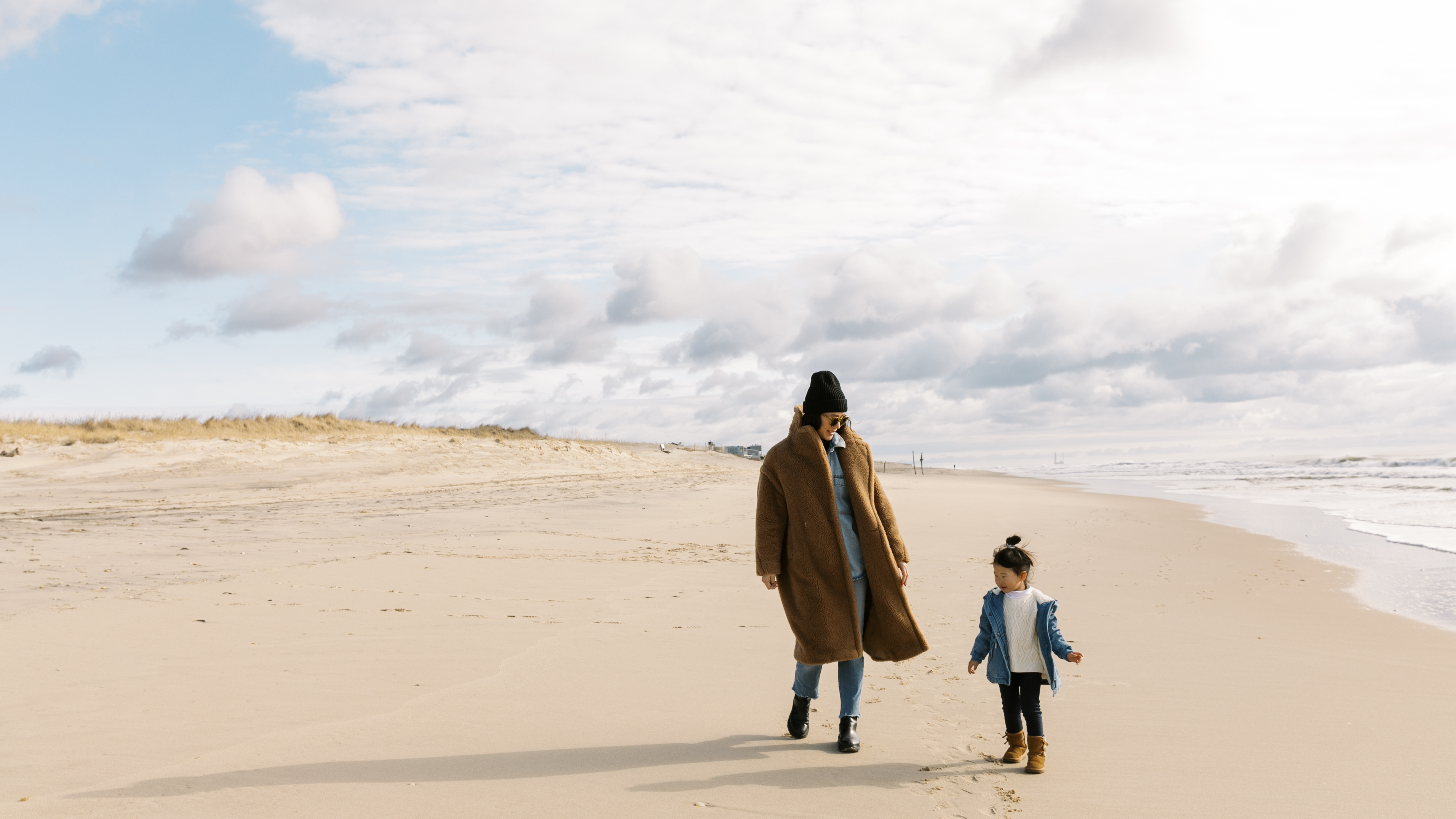 Mother & Child walking on beach in winter
