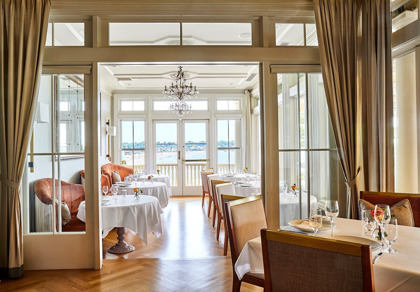 a formal dining room with white tablecloths and a view