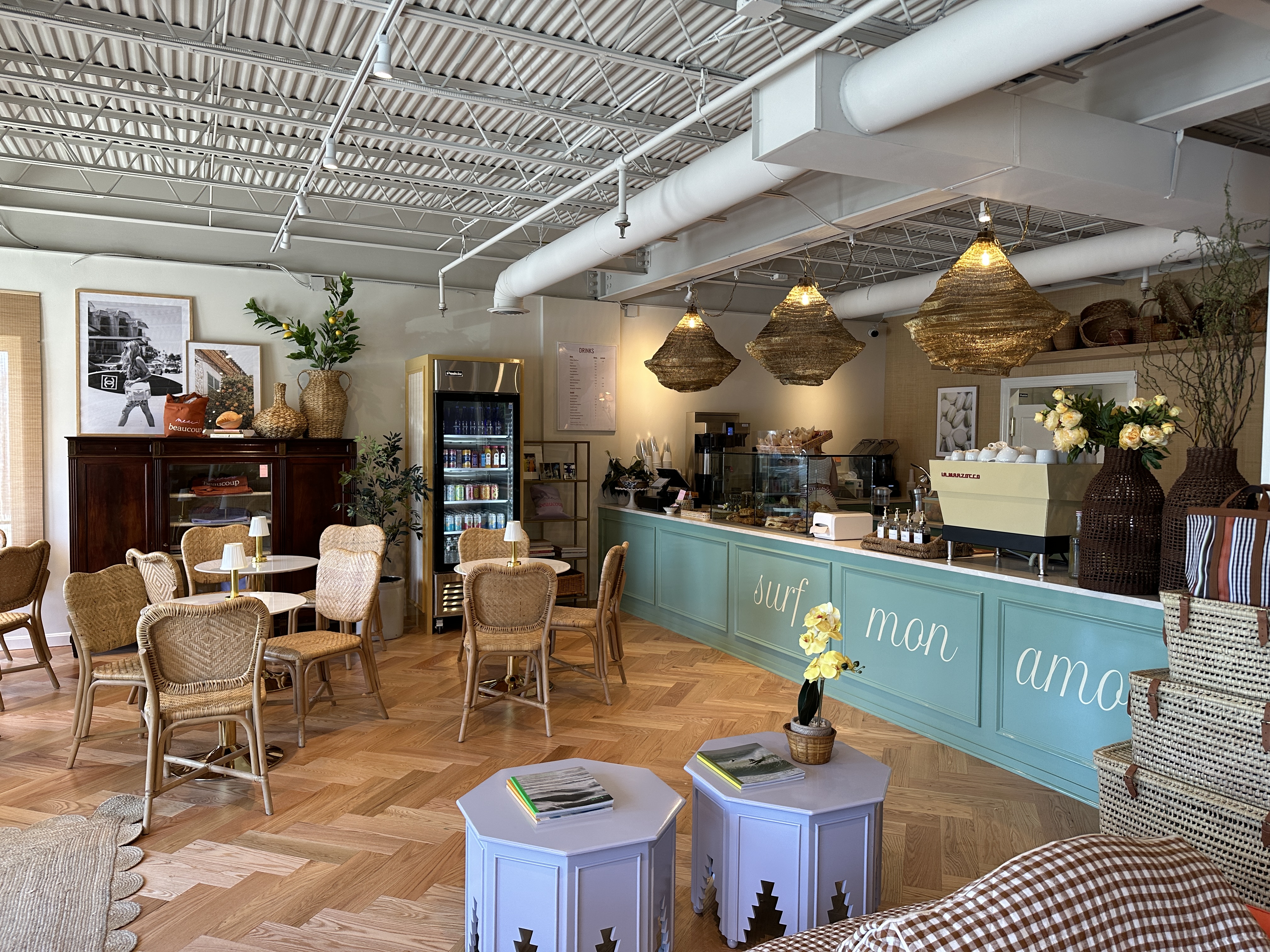A cozy lounge area with a coffee shop counter, wicker chairs, and decorative plants.