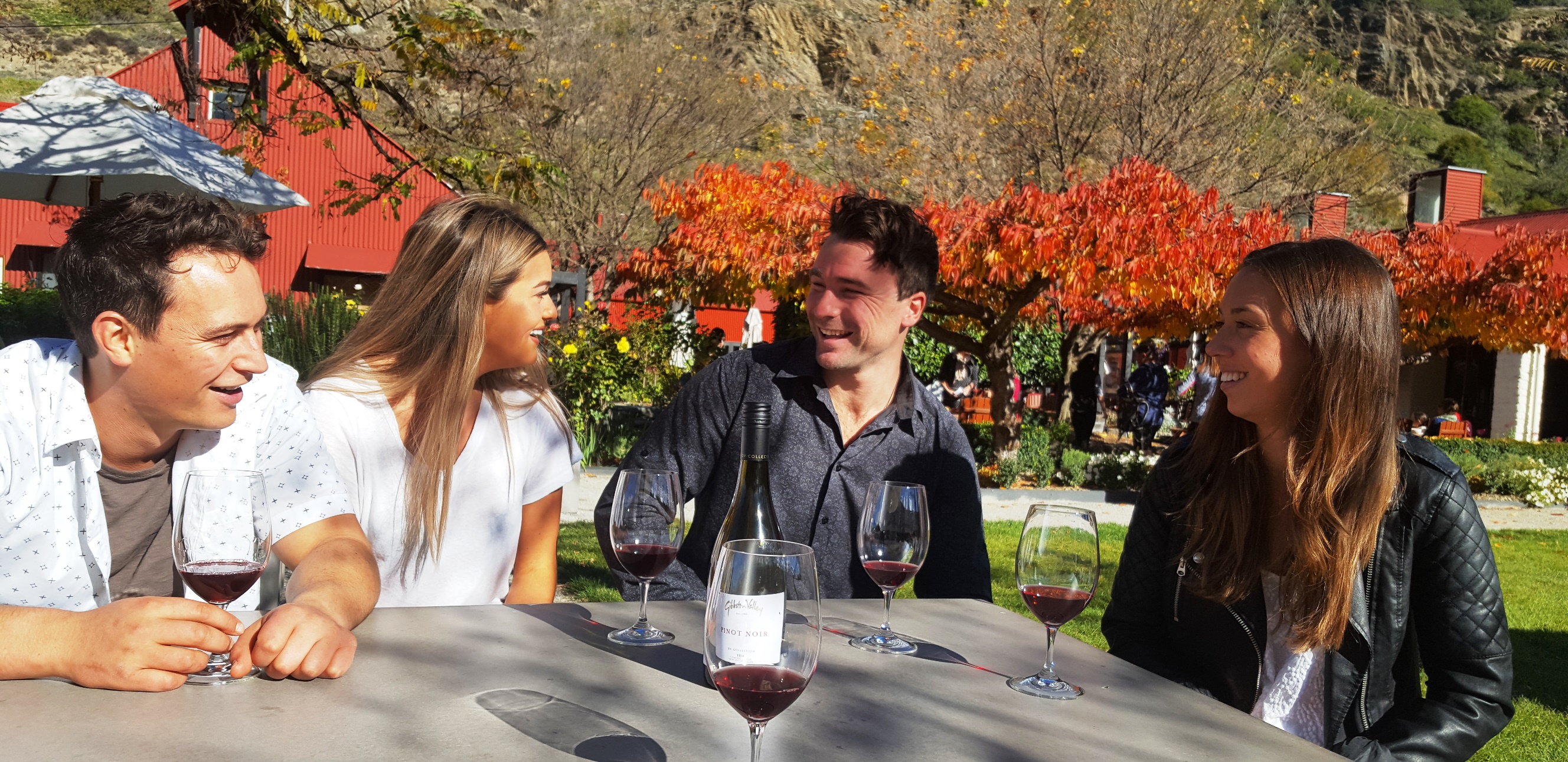 A group of friends laughing and enjoying wine tasting at a vineyard
