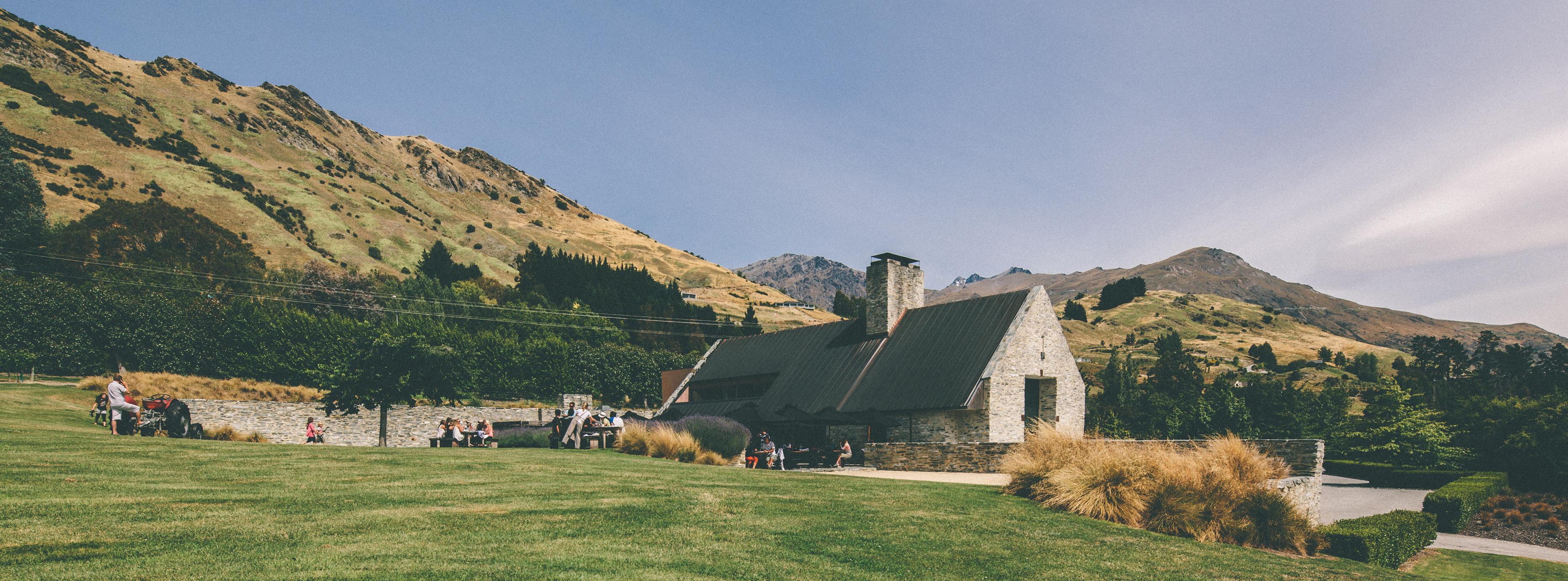 A sophisticated view of the Amisfield Queenstown winery nestled against the scenic backdrop of Lake Hayes and the mountains.