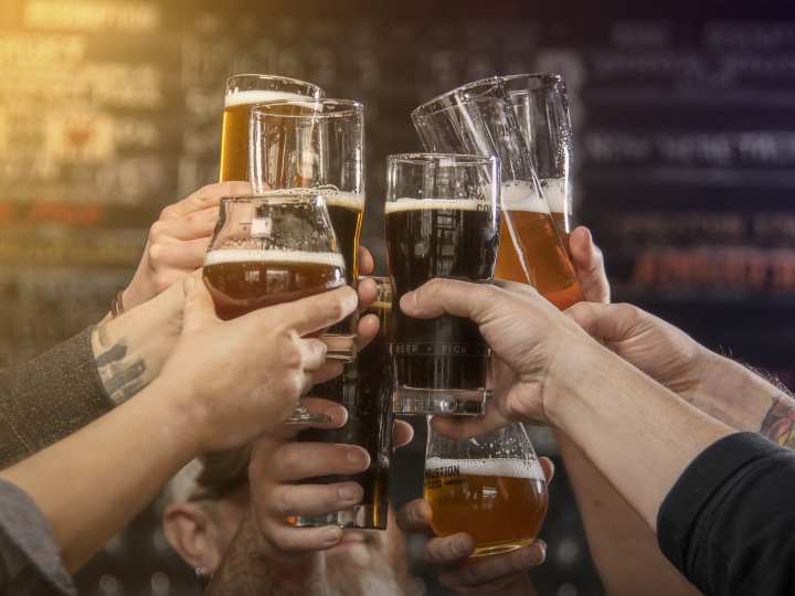 Group of hands clinking glasses at Combustion Brewery and Taproom