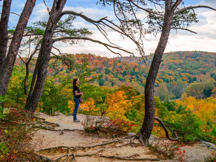 Woman standing at an overlook to look at fall foliage during a hike
