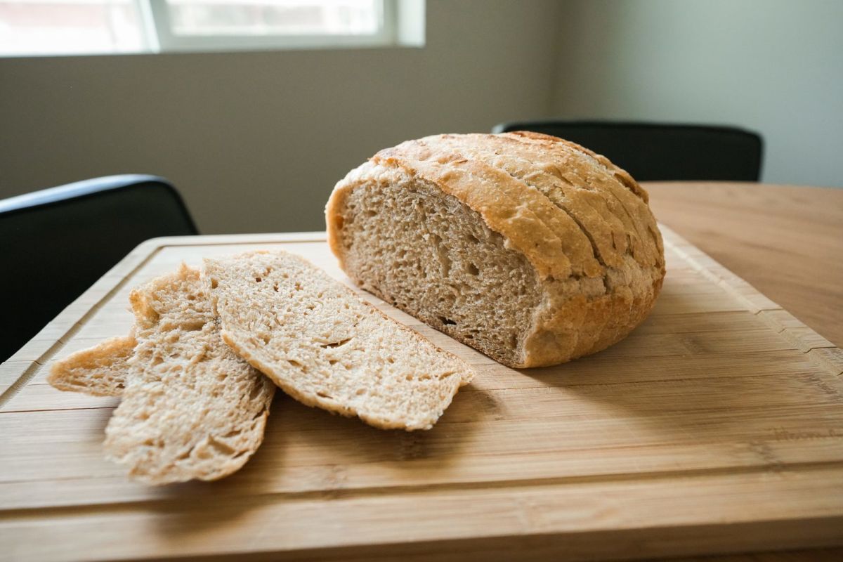 A round Dutch oven sourdough country loaf with two cut slices on a wooden board from Abigail’s Oven in Spanish Fork