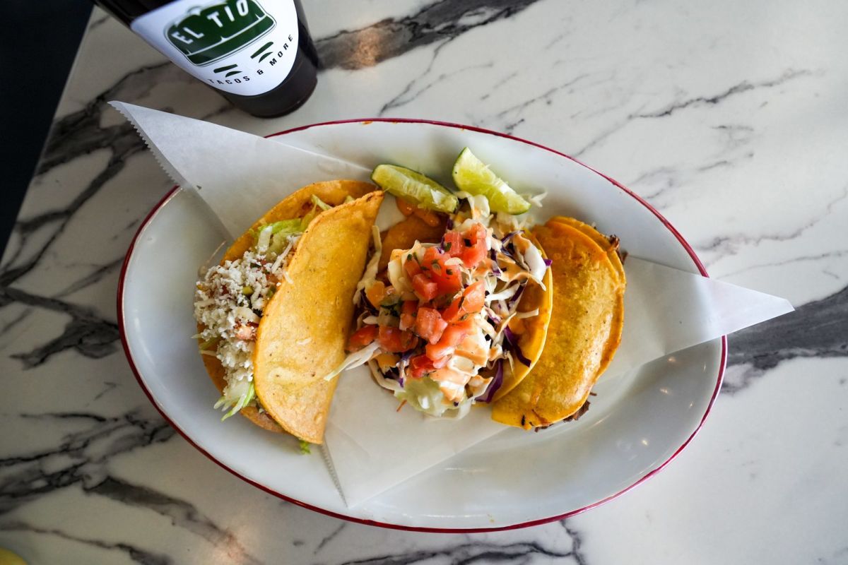 Two tacos topped with cabbage, pico de gallo and chipotle cream sauce on a plate at El Tio Tacos and More in Provo