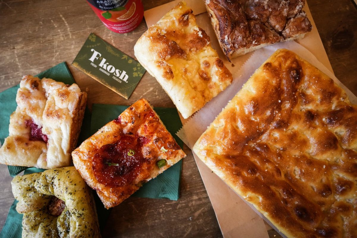 An assortment of focaccia loaves and weekly specialty slices spread across a table at F’kosh in Lehi
