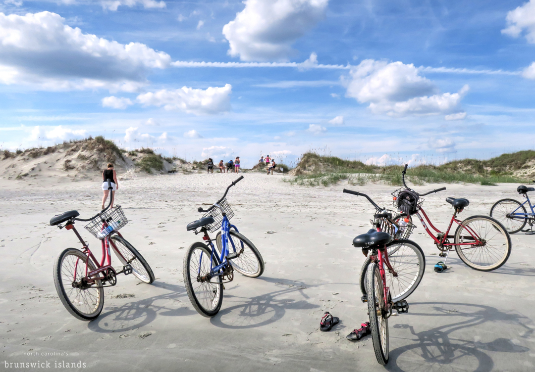 Bikes parked in the sand with people walking along the Brunswick Islands dunes