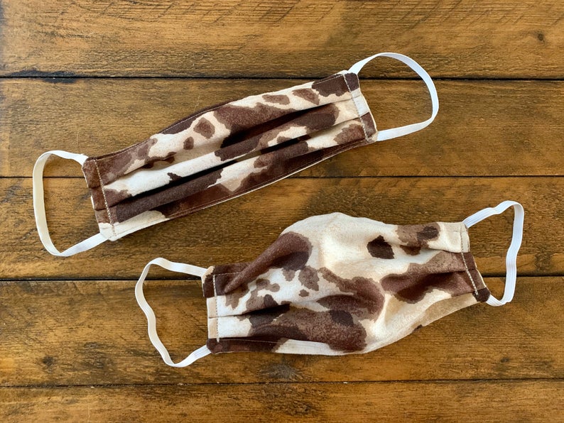 Medical masks made from fabric dyed to look like cowhide displayed on a wood background