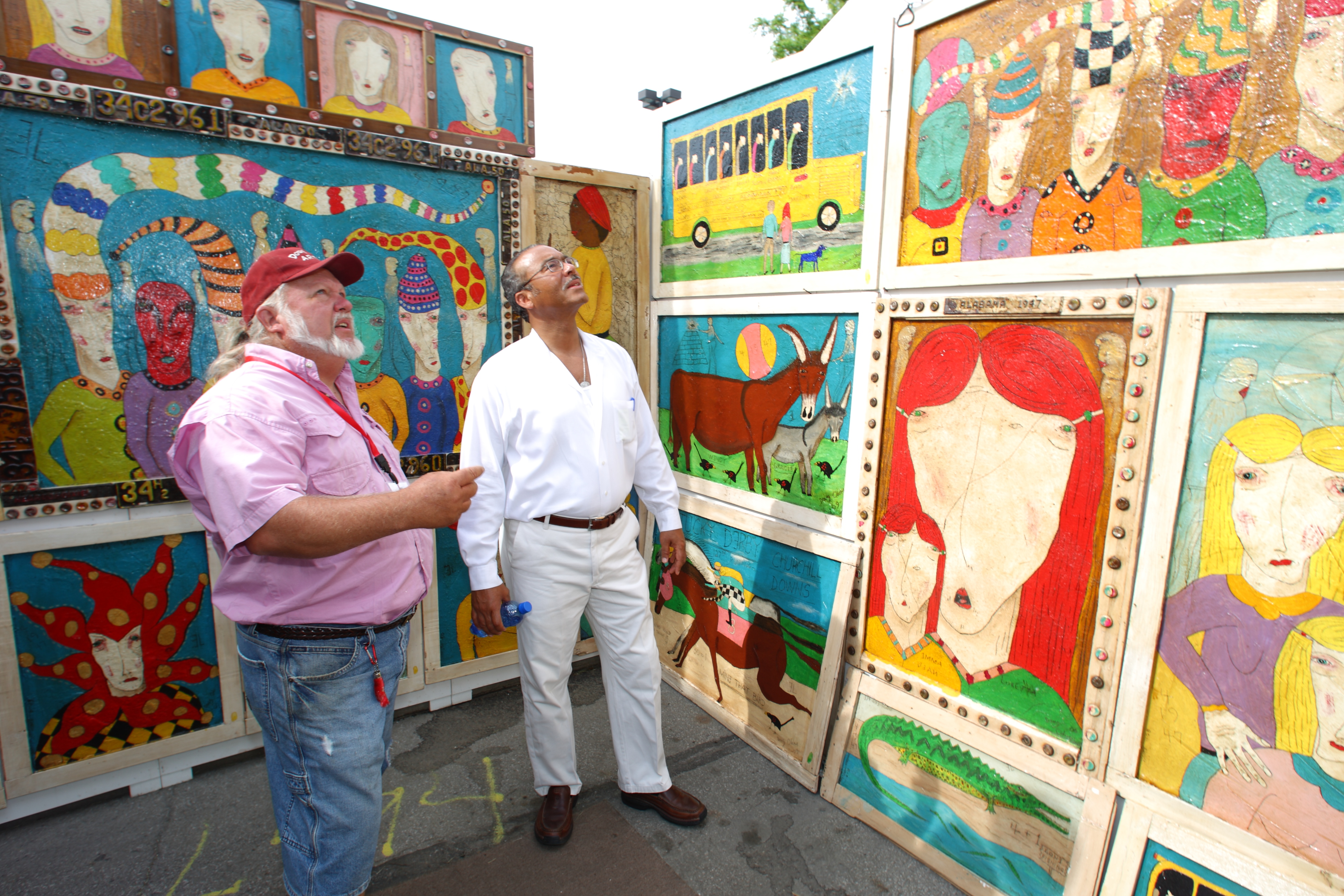 Two men admiring vibrant paintings inside vendor stall at the Columbus Arts Festival
