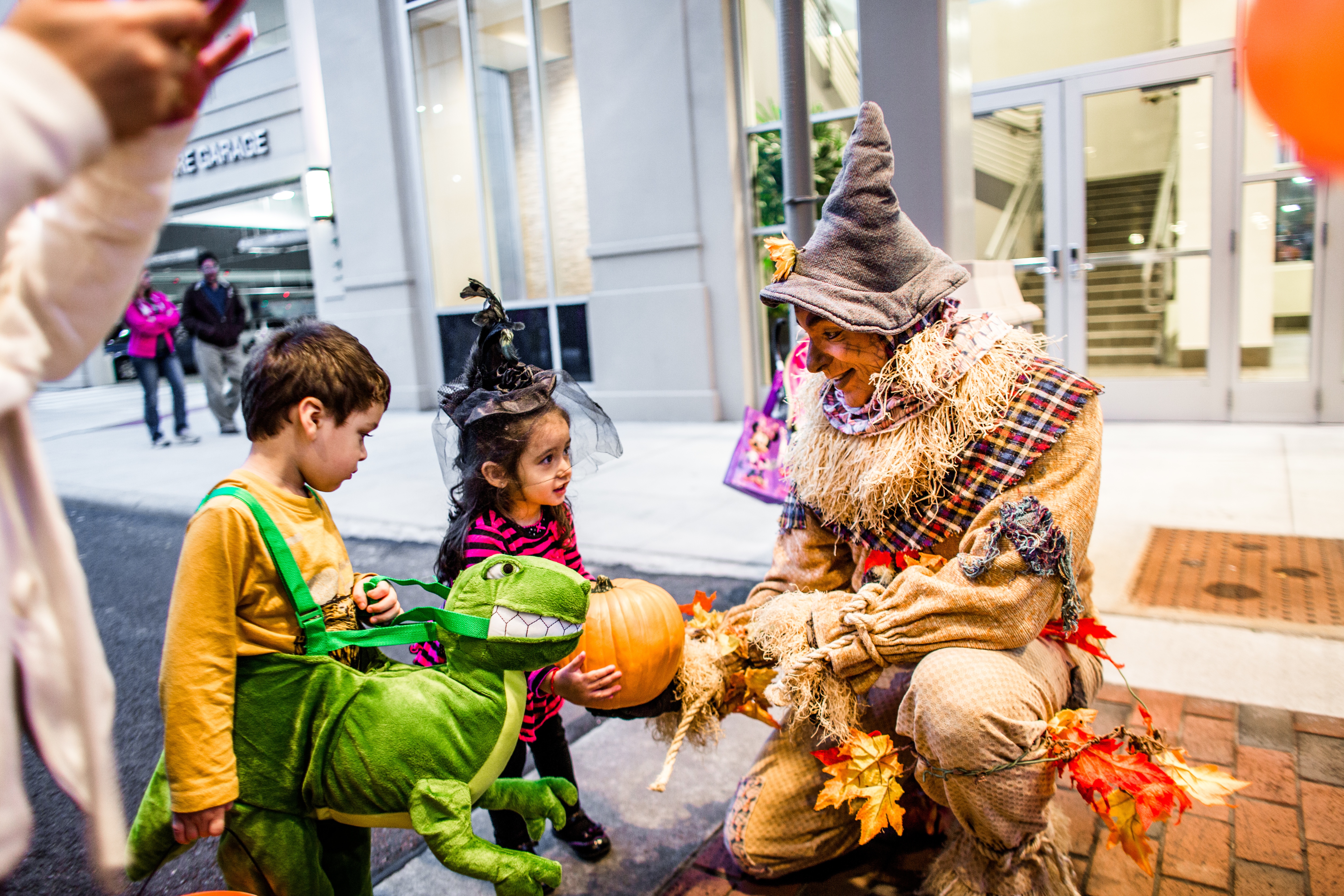 Two kids in costumes talking to adult in scarecrow costume