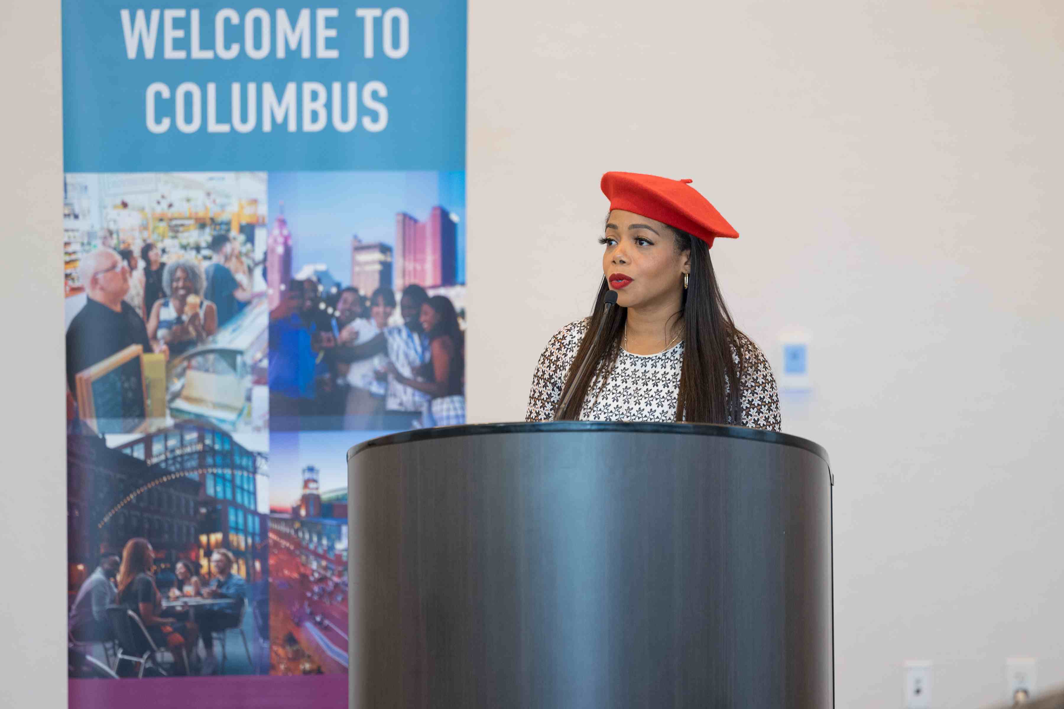 Speaker behind podium during AME press conference with Columbus sign in background